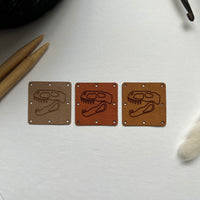 1.5” square ultrasuede tag, dinosaur skull