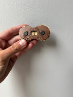 Wooden lock with decorative engravings held by a hand against a plain background